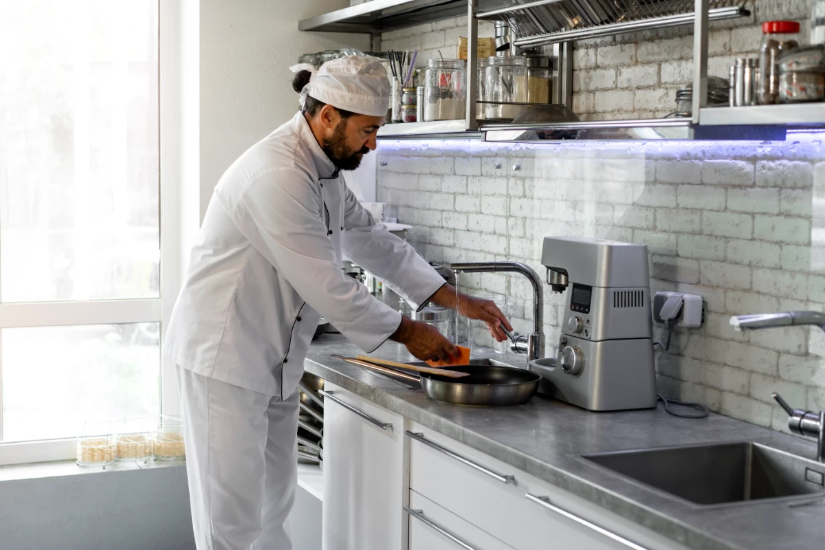 male chef kitchen washing frying pan
