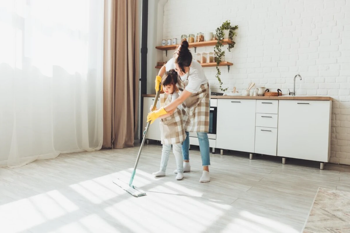 A little daughter and her mom clean the house 