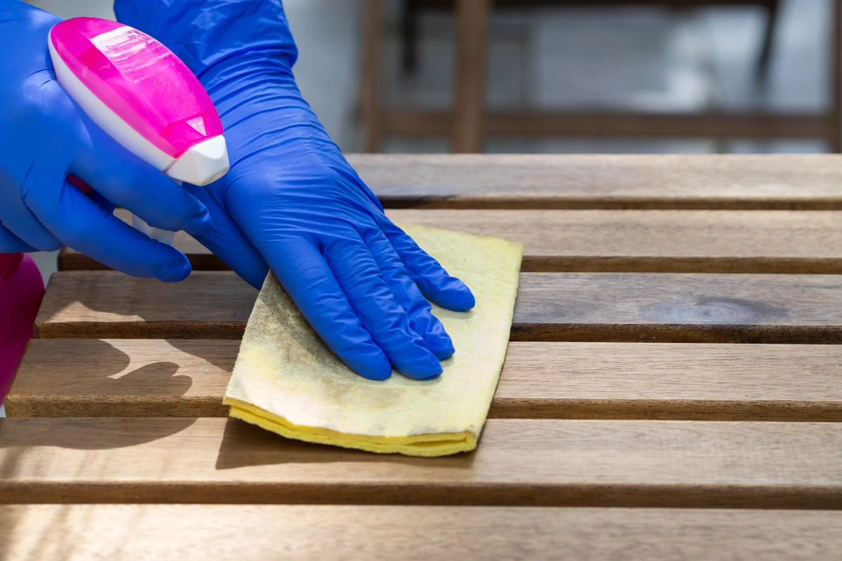 person disinfecting wooden surface