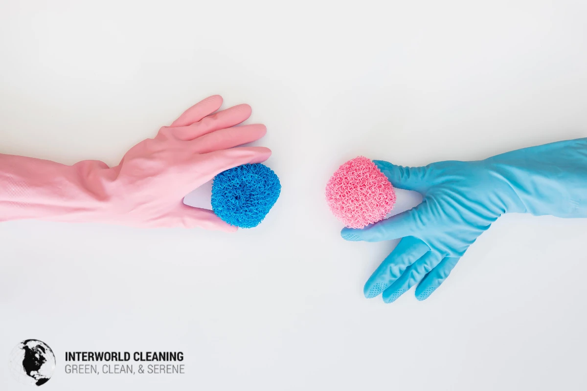Two gloved hands holding sponges reaching toward each other over a white background, symbolizing sharing the mental load of housework.