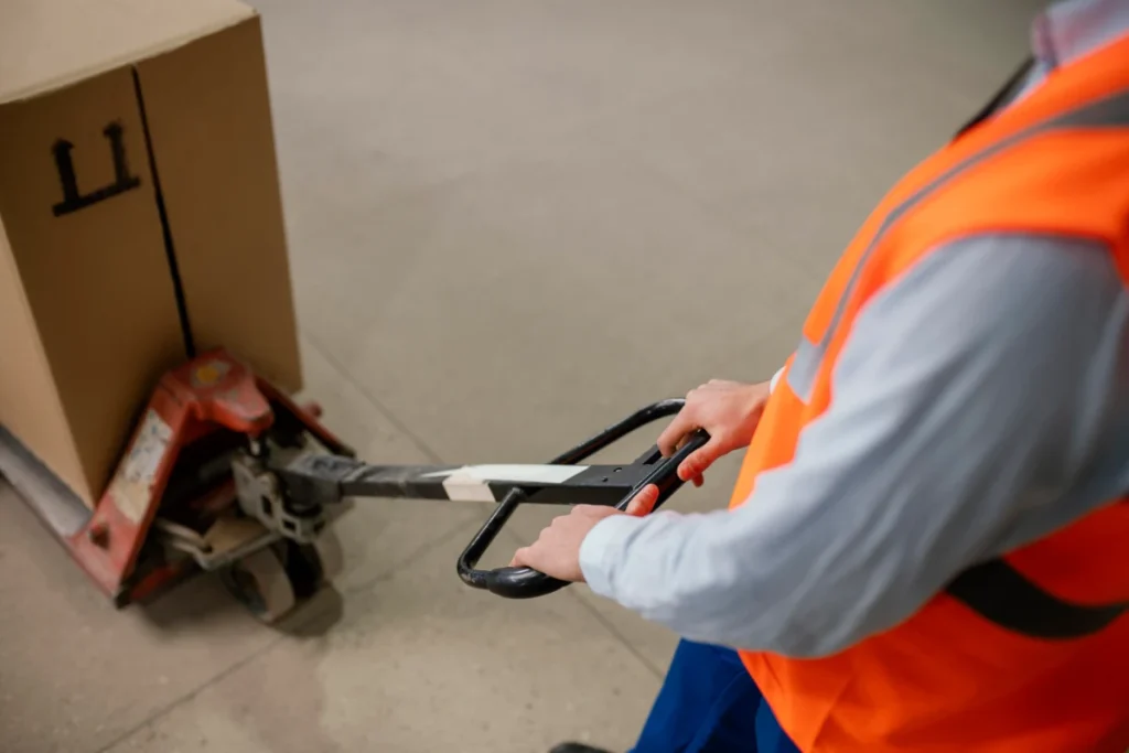 Close-up of worker handling pallet jack on warehouse floor
